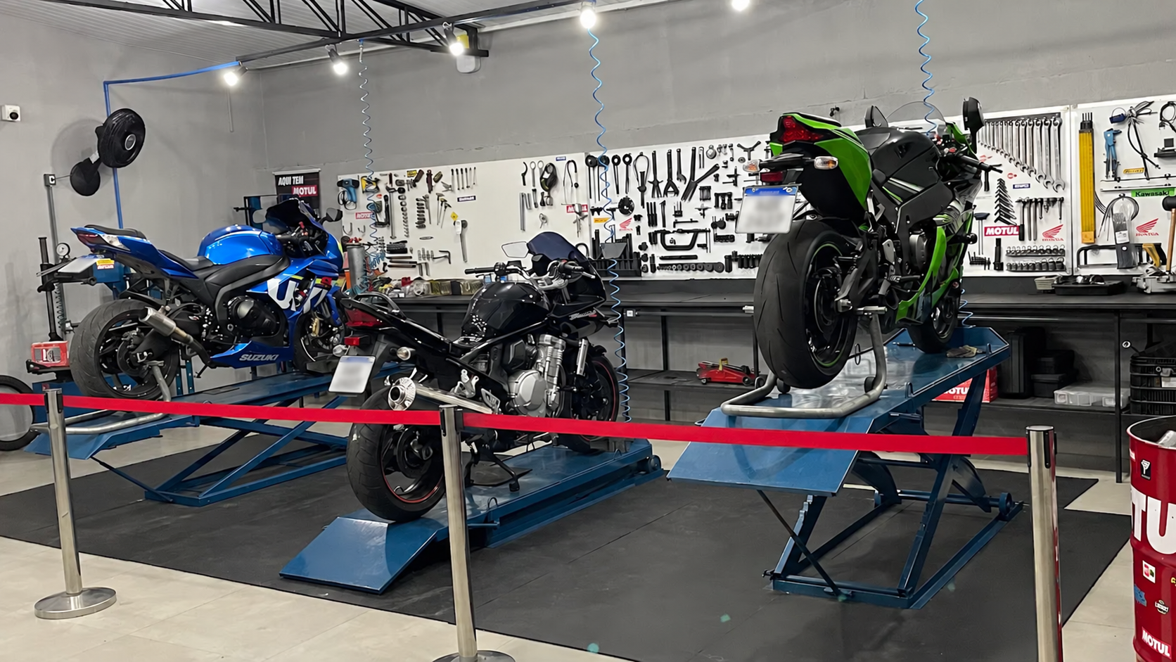 Área de trabalho da Forzza Motos, com três motocicletas nas plataformas e ferramentas organizadas